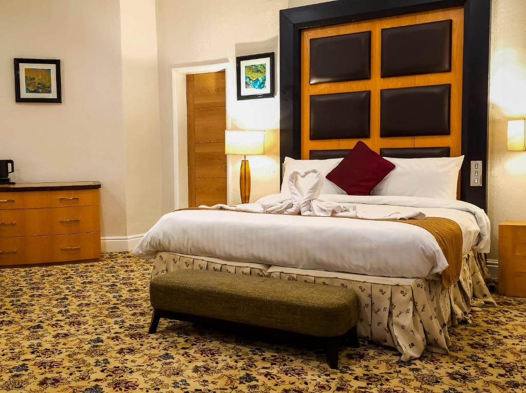 斯通Crown Hotel Stone的一间卧室配有一张大床,旁边设有长凳