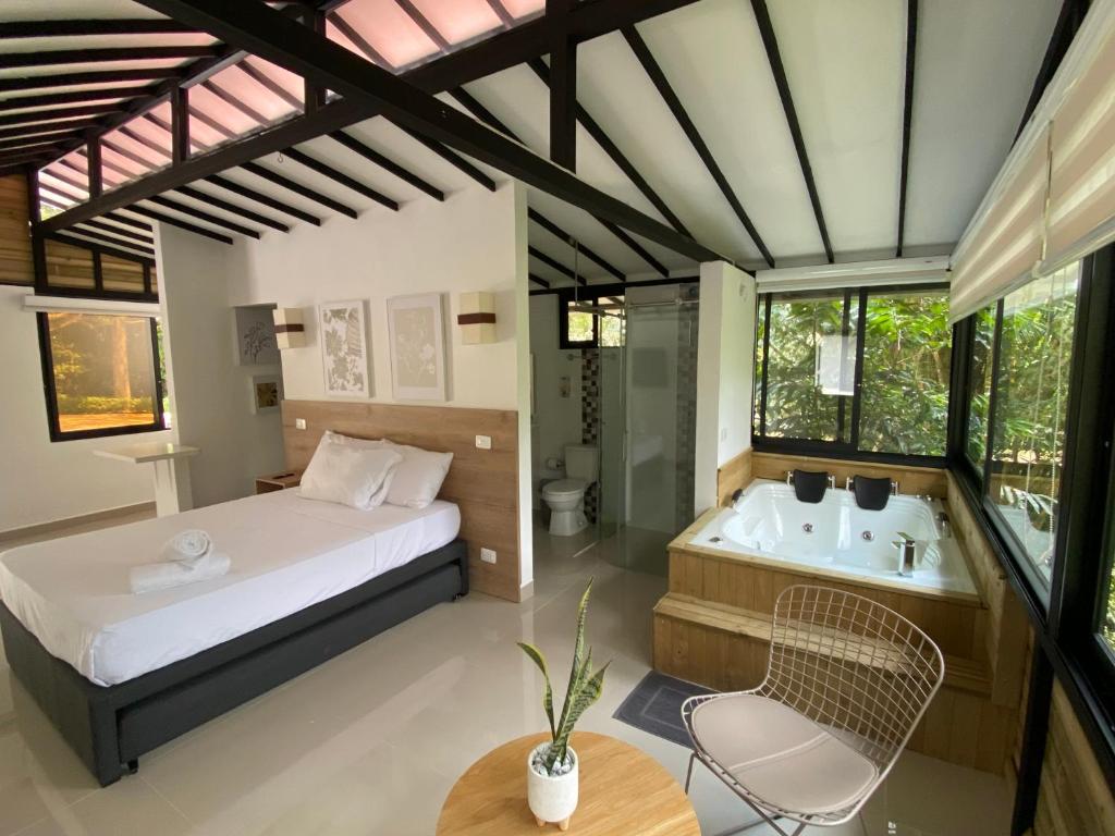 圣拉菲尔CRISTALES DEL RIO RESORT的卧室配有1张床、浴缸和桌子