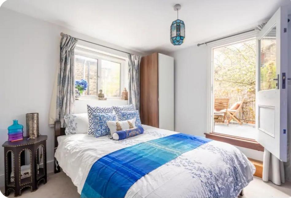 伦敦Stylish room with private bath and terrace in centrally located Clapham的一间卧室配有一张带蓝色和白色床单的床和窗户。