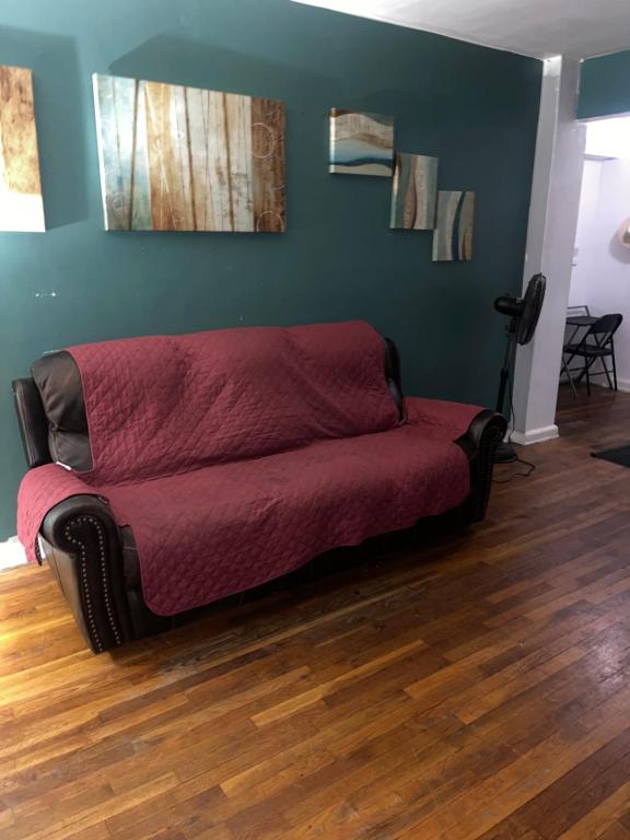 HollisComfy apartment的铺有木地板的客房内的红色沙发