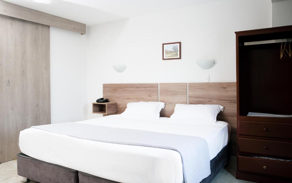 齐克拉约Hotel Santa Rosa的卧室配有一张白色大床和木制床头板