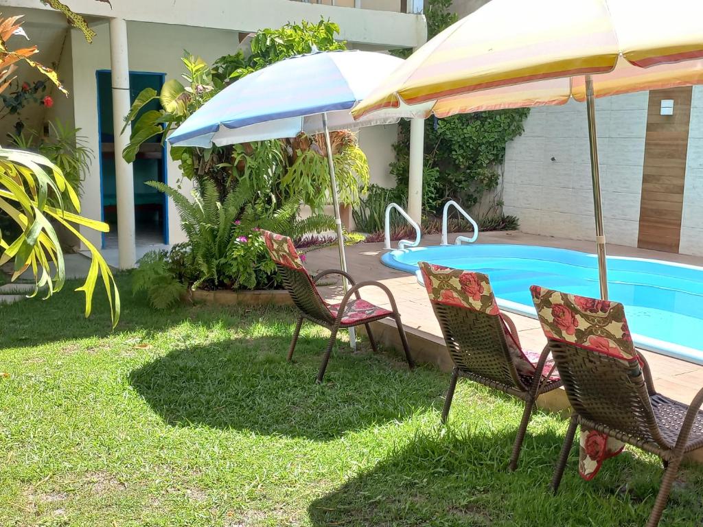 伊塔乌纳斯Pousada Cajueiro的一组椅子和遮阳伞,位于游泳池旁