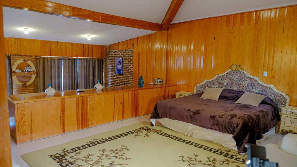 小米内拉尔Cabañas- Casas España的一间带木墙的卧室和一张位于客房内的床
