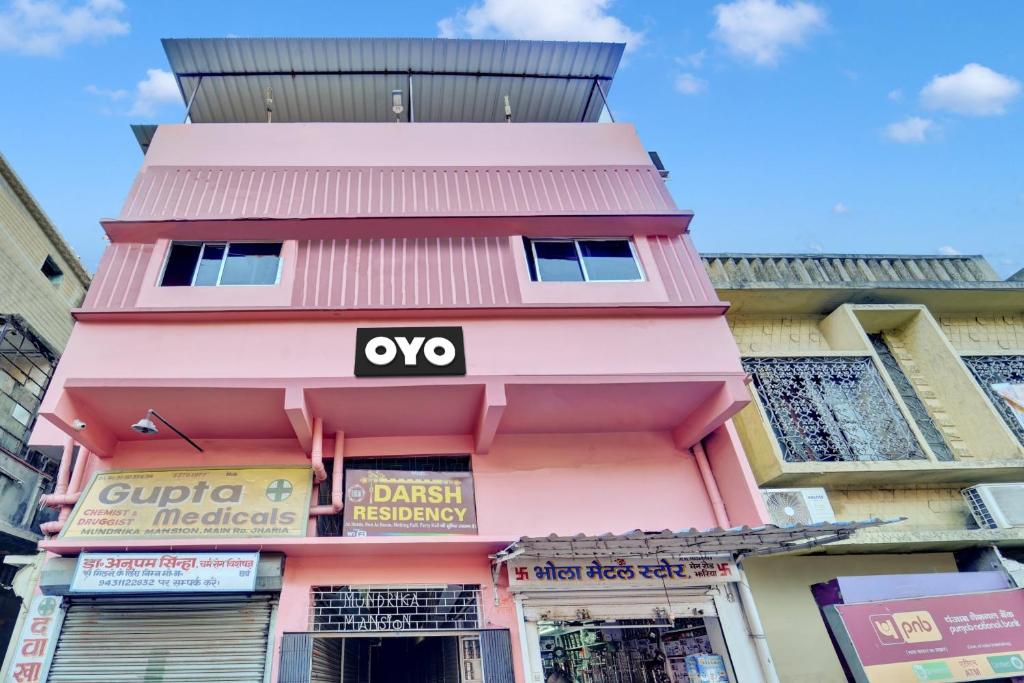 丹巴德OYO Flagship Darsh Residency的粉红色的建筑,上面有牛 ⁇ 标志