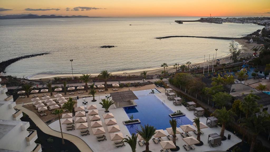 普拉亚布兰卡Dreams Lanzarote Playa Dorada Resort & Spa的享有带游泳池和海滩的度假村的空中景致