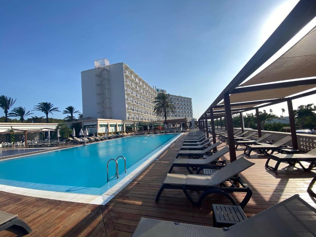 萨尔加Alua Illa de Menorca的一个带躺椅的游泳池和一间酒店