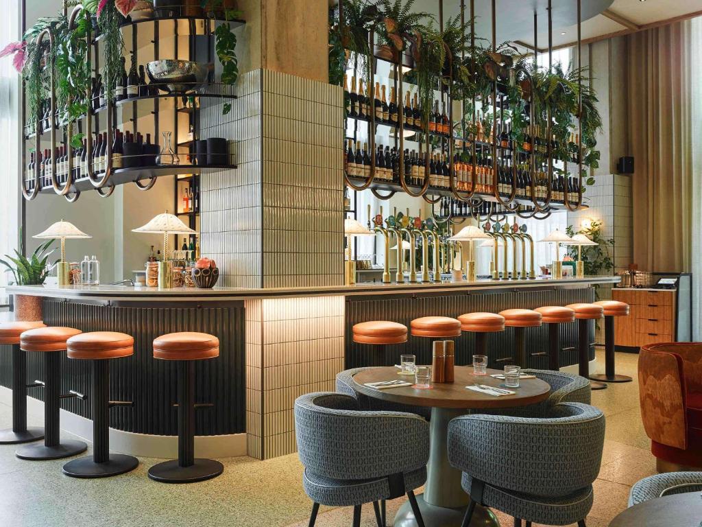 伦敦TRIBE London Canary Wharf的餐厅设有酒吧,配有桌子和凳子