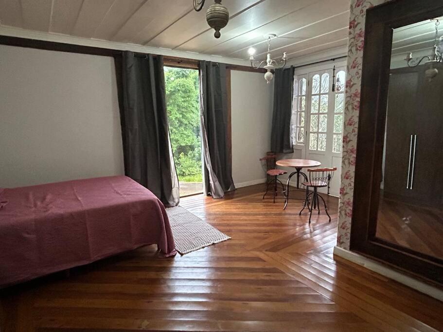 蒂拉登特斯Casa Temporada recanto de minas的客房设有一张床和一张桌子及椅子