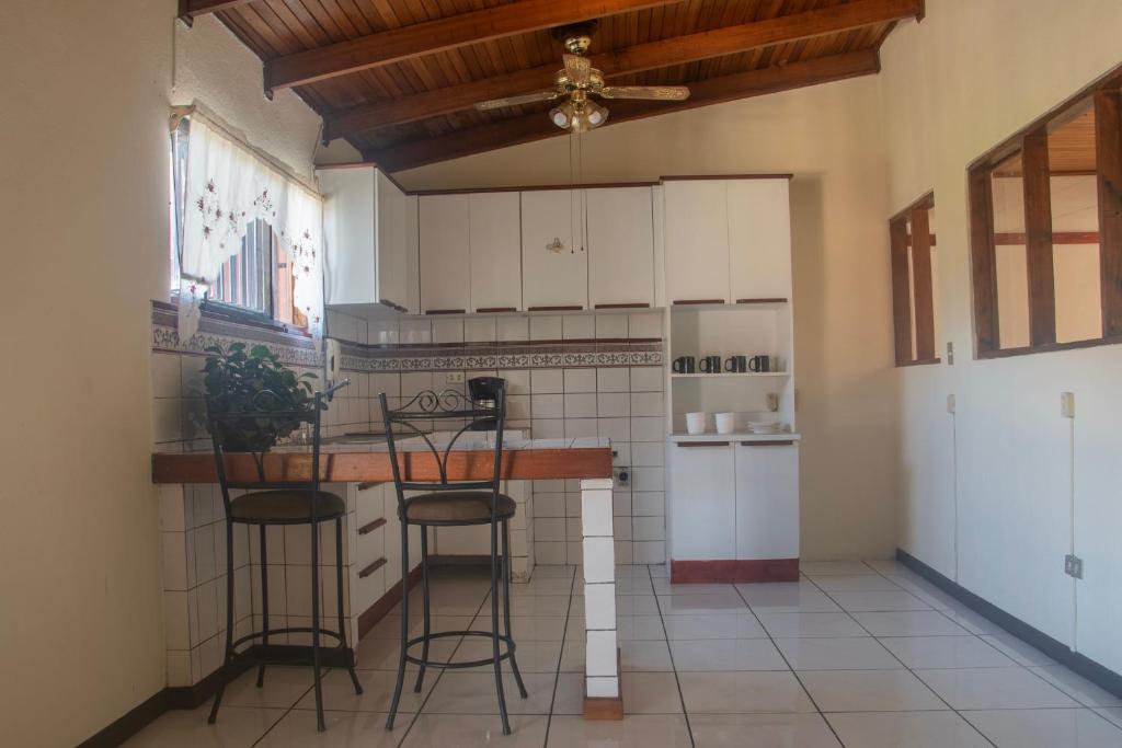 阿拉胡埃拉Casa Calas的厨房配有白色橱柜和带凳子的台面
