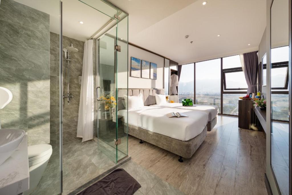 芽庄Ivy Hotel Nha Trang的一间卧室设有一张床和一个玻璃淋浴间