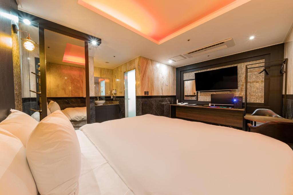 首尔Hotel Signature的卧室配有一张白色大床和一台平面电视。