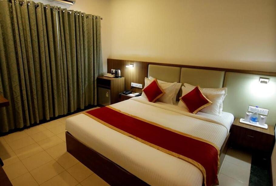 FerokhHOTEL CALICUT GATE的酒店客房配有一张带红色枕头的大床