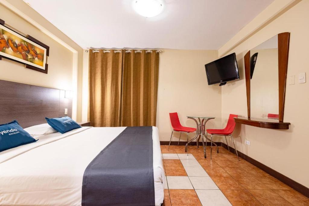 利马Hotel Caribe的酒店客房带一张床、一张桌子和椅子
