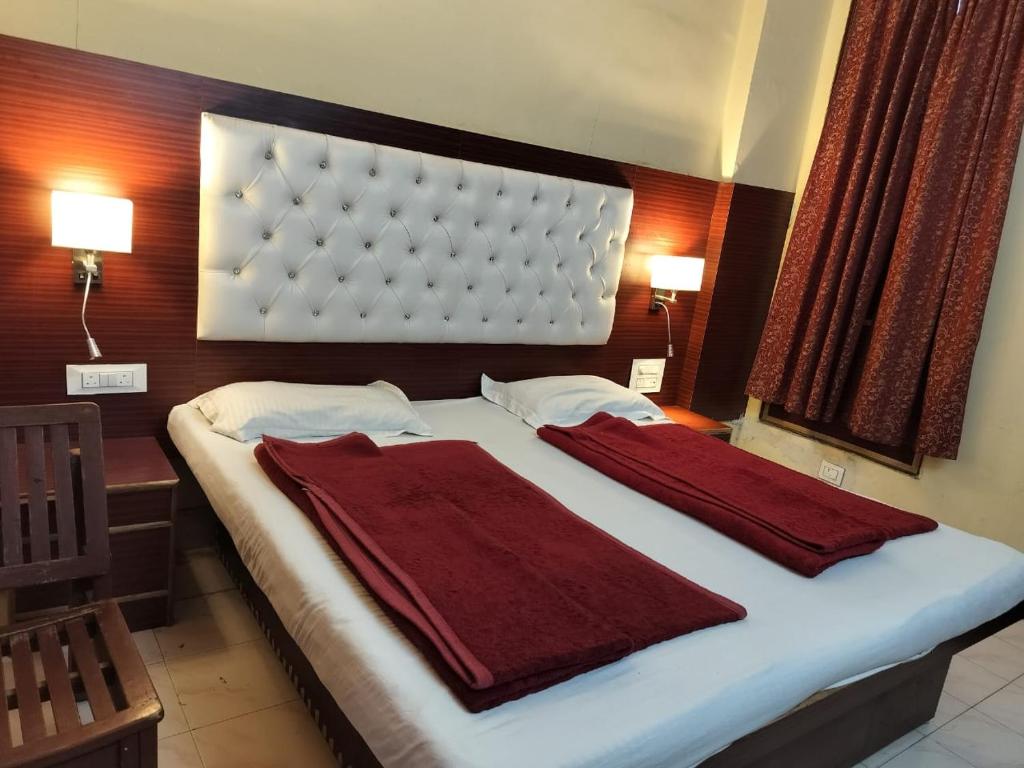 新德里王子宫殿酒店（绿色酒店）的一间卧室配有一张大床,上面有两条红色毛巾
