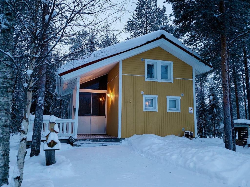 罗瓦涅米Lapland Forest Lodge的一座小黄色房子,地面上积雪