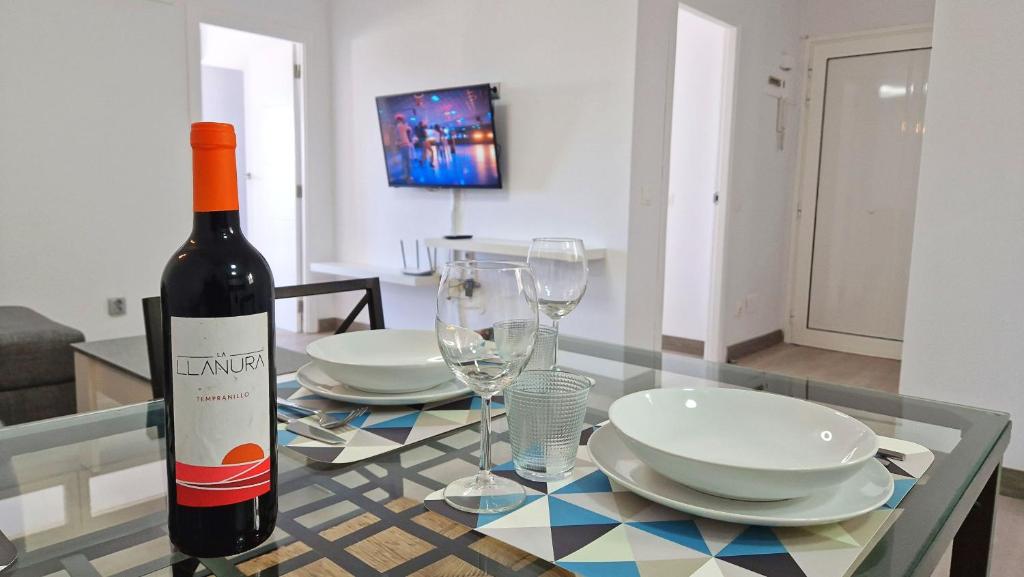 阿德耶Atalaya - Sea View的玻璃桌旁的一瓶葡萄酒,带盘子和玻璃杯