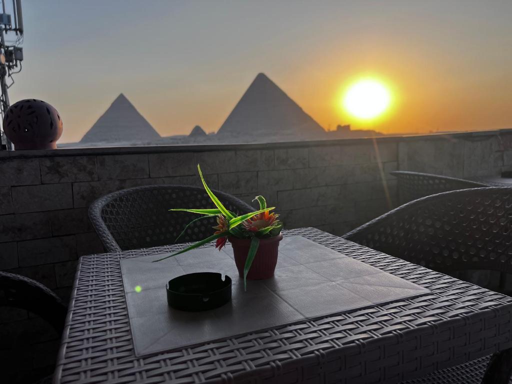 开罗Aton pyramids INN的阳台上的桌子上放着植物,享有日落美景