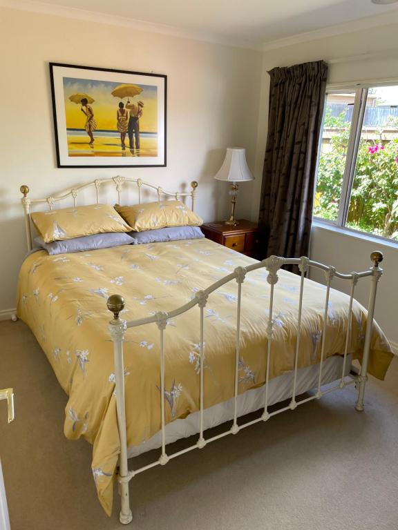 帕拉帕拉乌穆Spacious Home的卧室配有白色床、黄色床单和窗户。