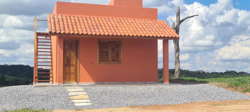 圣托梅-达斯莱特拉斯Pousada Colina das Maritacas的石子顶上有一个橙色屋顶的小房子