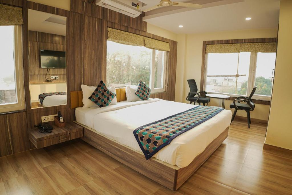 贾姆谢德布尔Hotel Grand Residency的一间卧室配有一张大床和一张桌子及椅子