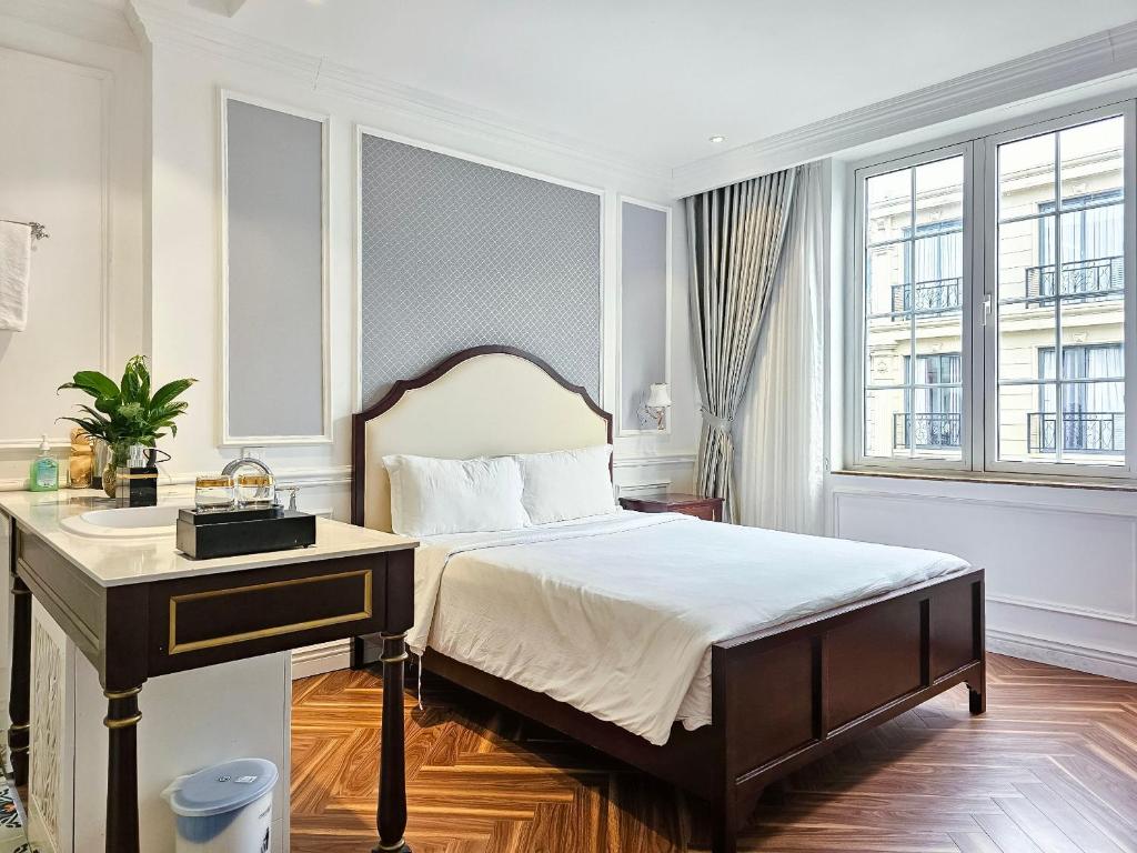 胡志明市Diamond Boutique Hotel 36的一间卧室配有一张带书桌的床和一张四柱床。