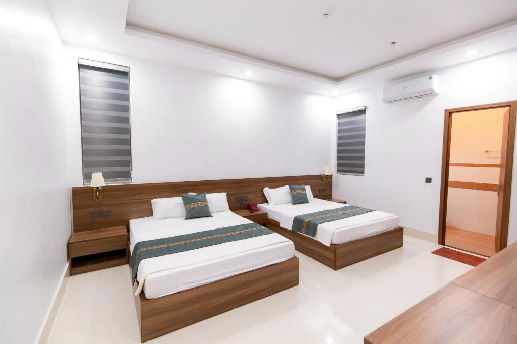 Xóm Soi (2)Khách sạn Vạn Phúc - Yên Bái的白色墙壁客房的两张床