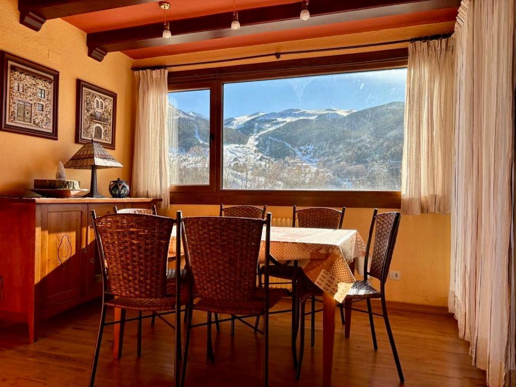 塞尔勒La casita de Cerler的一间带桌椅和大窗户的用餐室