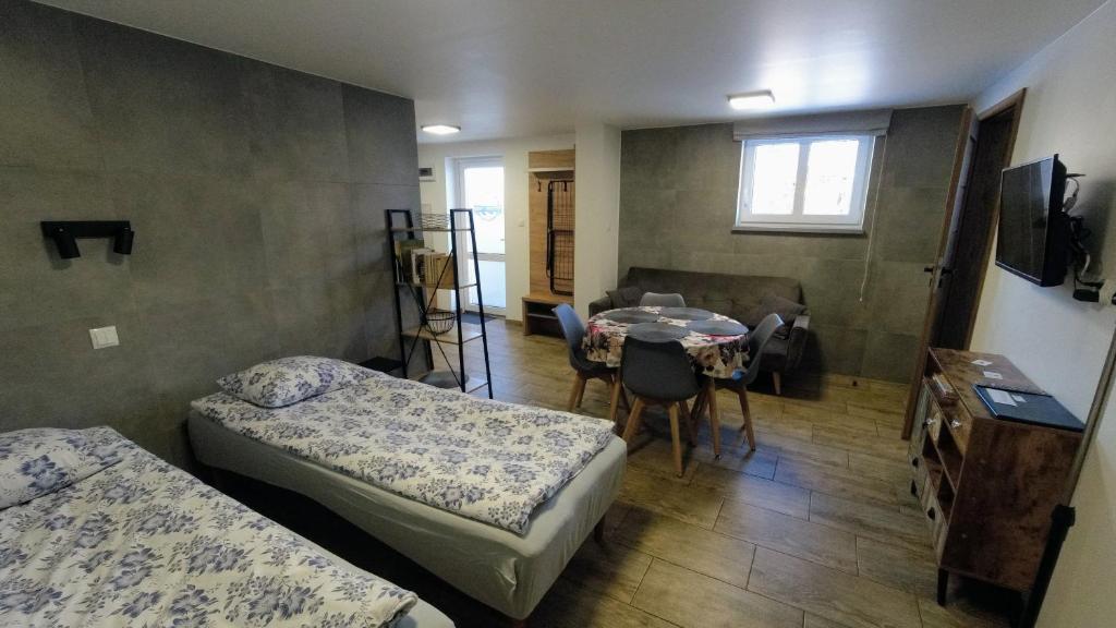 蒂科钦Przystanek Tykocin - apartamenty gościnne的一间带两张床和一张桌子的房间和一间带用餐室的房间