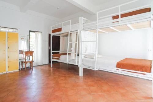 沙努尔Bali Telaga Hati Yoga Healty And Retreat Center的一间卧室设有白色双层床,铺有木地板