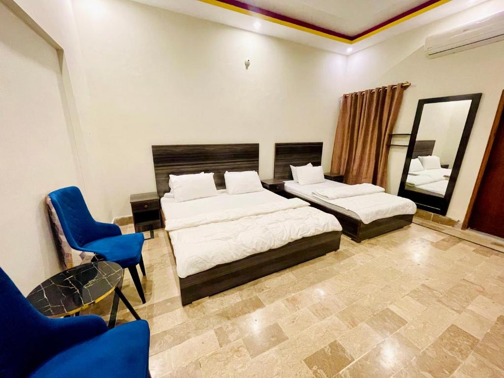 卡拉奇Airport Hotel Bed & Rest的一间卧室配有两张床和一张蓝色椅子