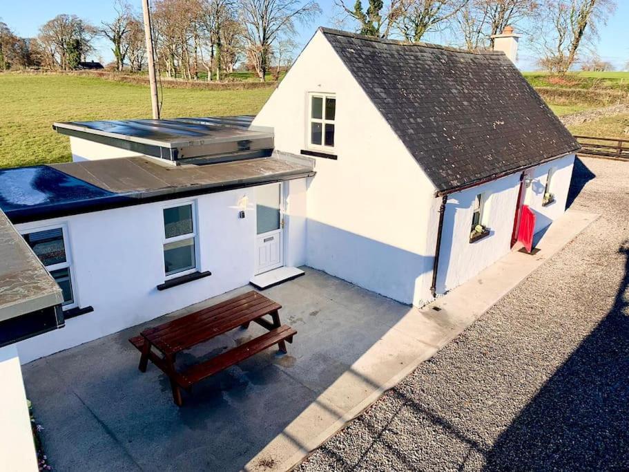 CarneyIrish Cottage Tipperary的前面有长凳的小白色建筑