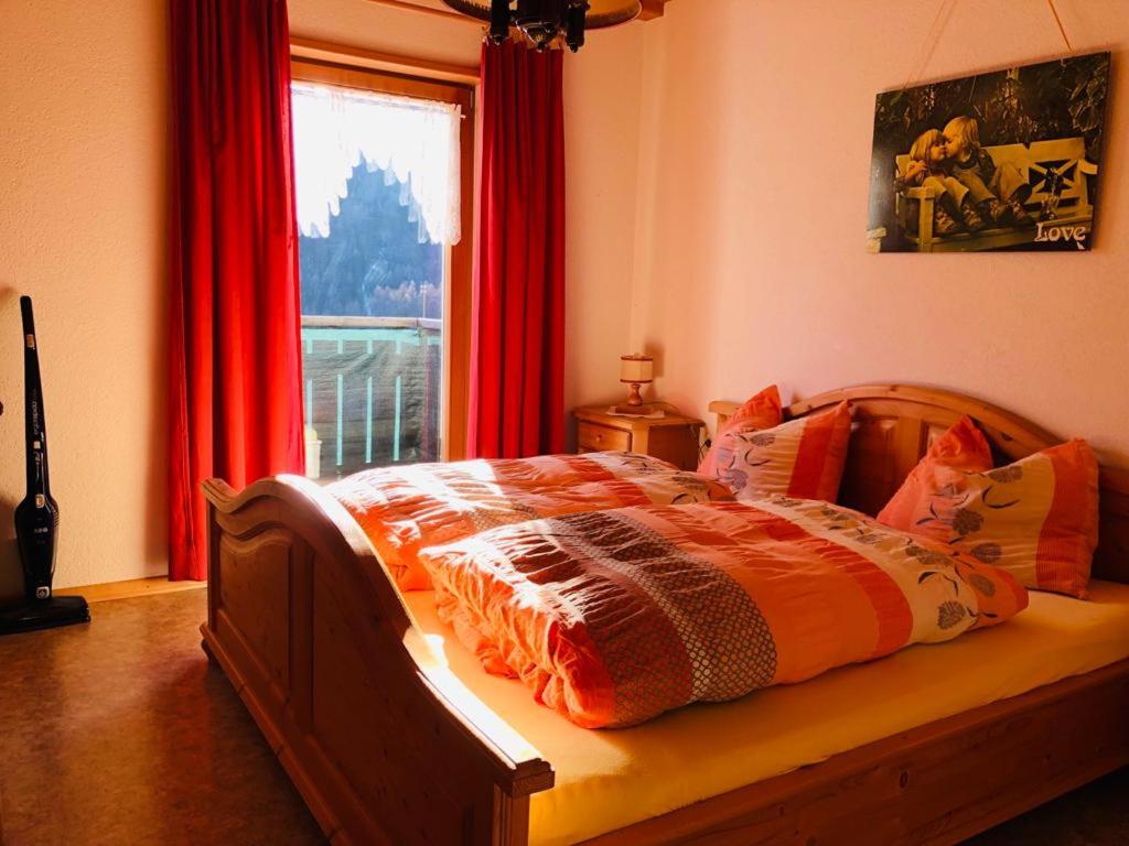 普拉托·阿罗·斯泰尔维奥Egghof的卧室内的一张床位,卧室的窗户配有红色窗帘
