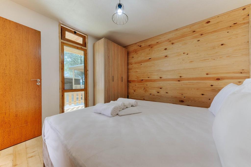 乌尔齐尼Family Bungalows的卧室配有白色的床和木墙