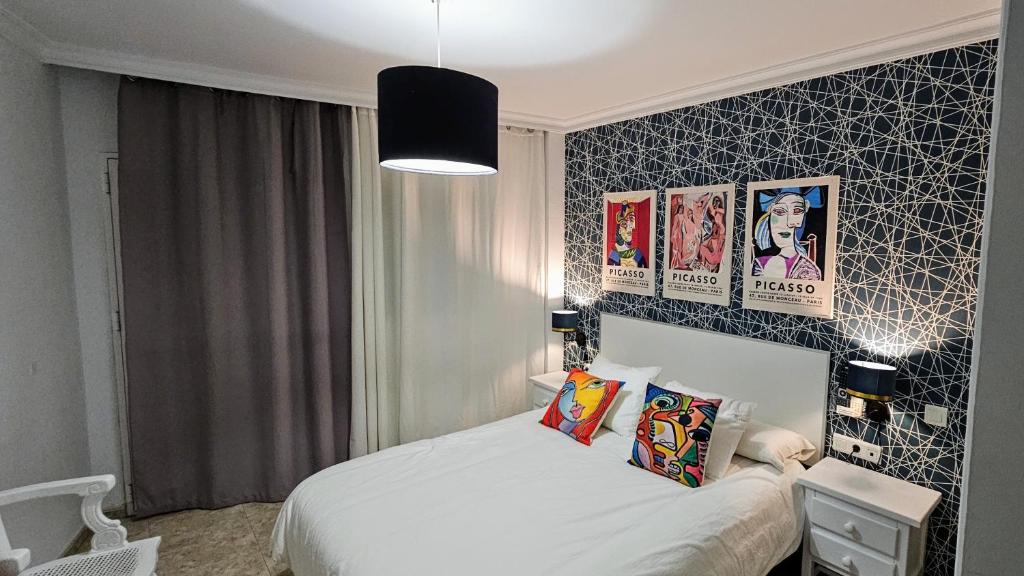 内尔哈Hostal Luna de Nerja HMA 02340的一间卧室配有一张床,墙上挂着一些图片