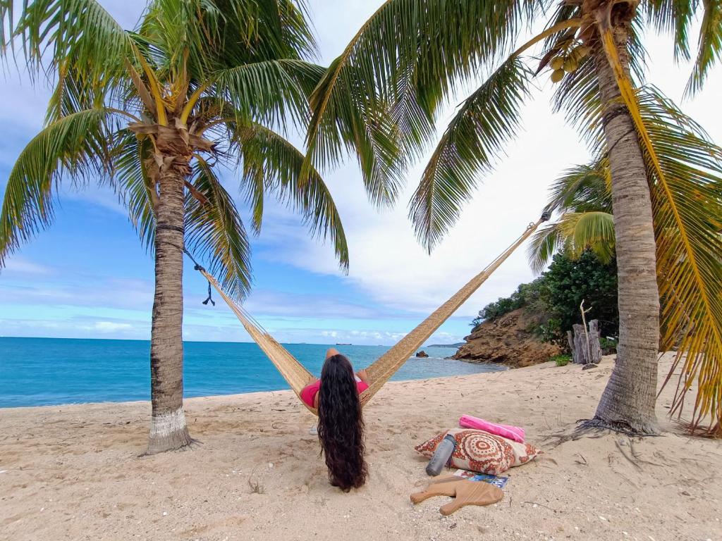 Five Islands VillageComfy house on a hidden beach的躺在海滩上吊床上的女孩