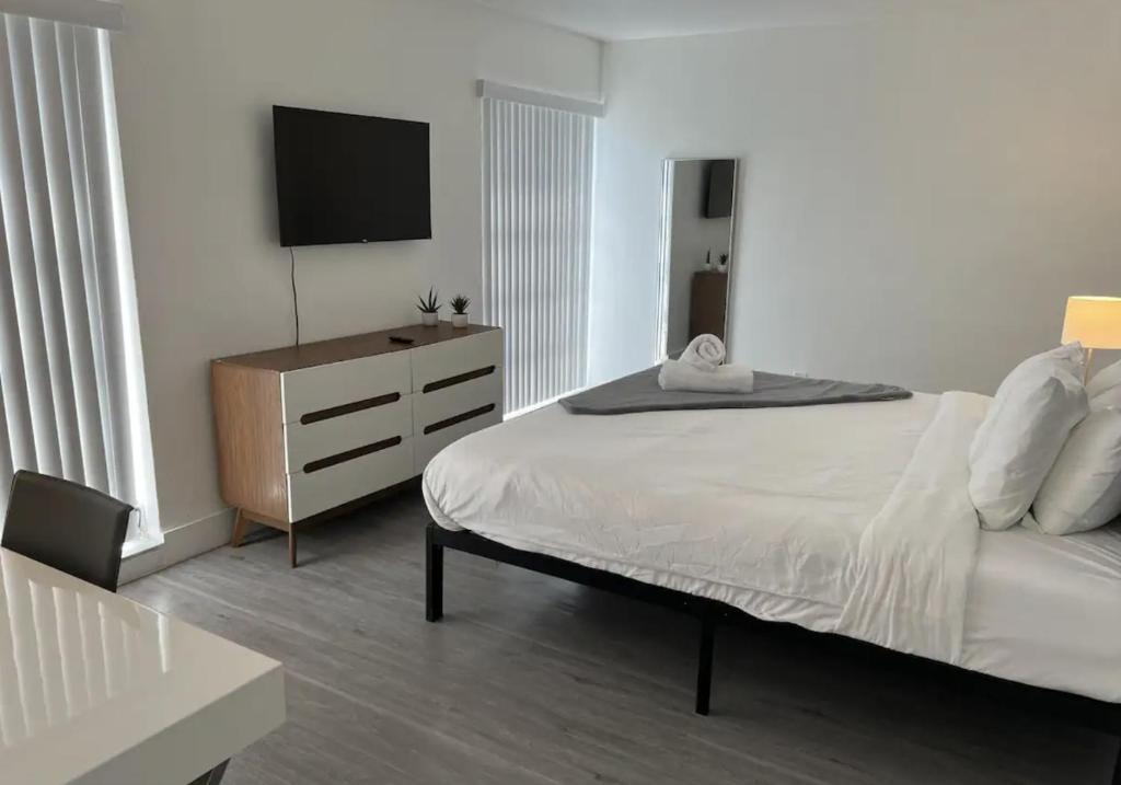 劳德代尔堡Designer River View Apartments的一间卧室配有一张床和一个带电视的梳妆台