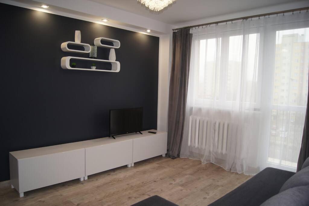 科沙林Mieszkanie osiedle Północ的客厅设有一台位于黑色墙壁上的平面电视。