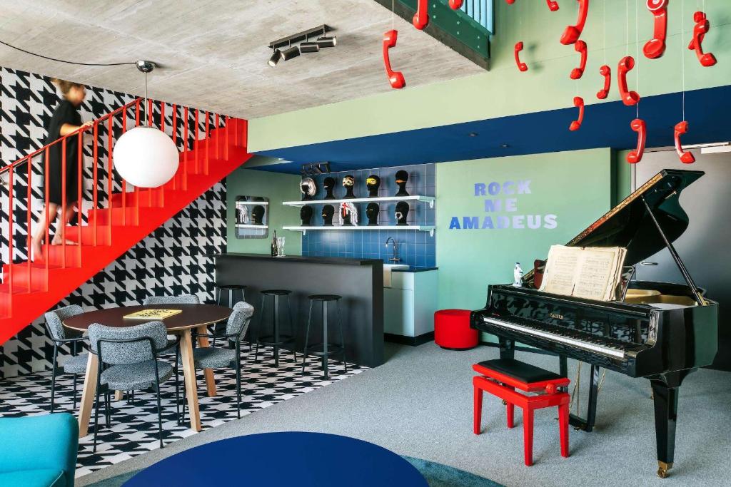 维也纳The Social Hub Vienna的一间设有钢琴、桌子和酒吧的房间