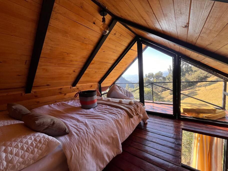 SesquiléCabaña tu.terra “El Paraíso”的木制客房的一张床铺,设有大窗户