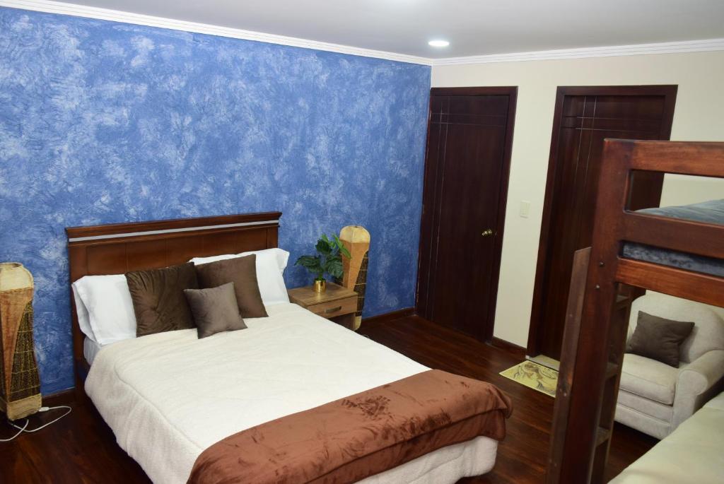 昆卡Hostería La Travesía Campiña的一间卧室设有一张床和蓝色的墙壁