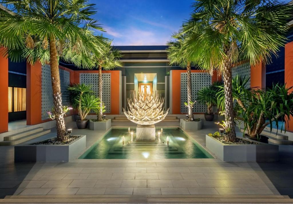 华欣Phukalini Luxury Pool Villa & Onsen-SHA Plus Certified的棕榈树的寺庙和灯光的山脊