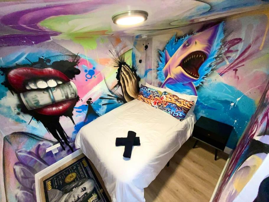 迈阿密Cozy & Colorful Miami Art Canvas w/HotTub & Murals的卧室,卧室内有一张床铺的绘画