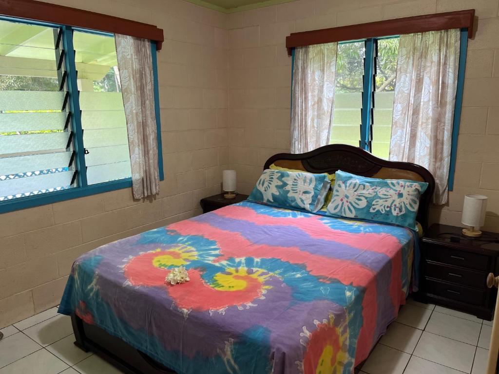 阿瓦鲁阿Sharnyta’s Guesthouse的一间卧室配有一张色彩缤纷的床和两个窗户