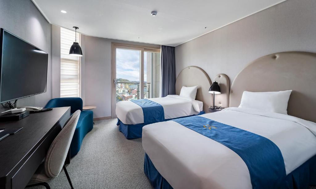 晋州市Golden Tulip Essential Namgang的酒店客房设有两张床和一台平面电视。