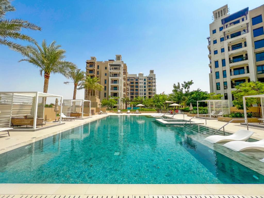 迪拜FAM Living - Serene 1BR Haven in Madinat Jumeirah Living的一座棕榈树和建筑的大型游泳池