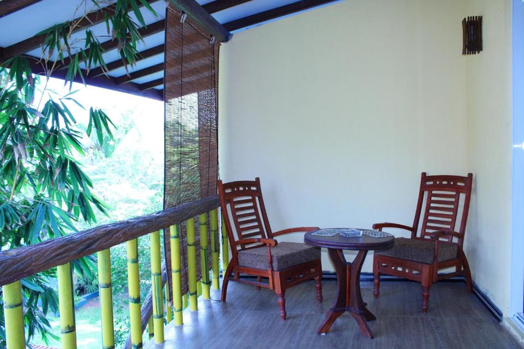 瓦都瓦Raj Mahal Inn的阳台的门廊配有2把椅子和1张桌子