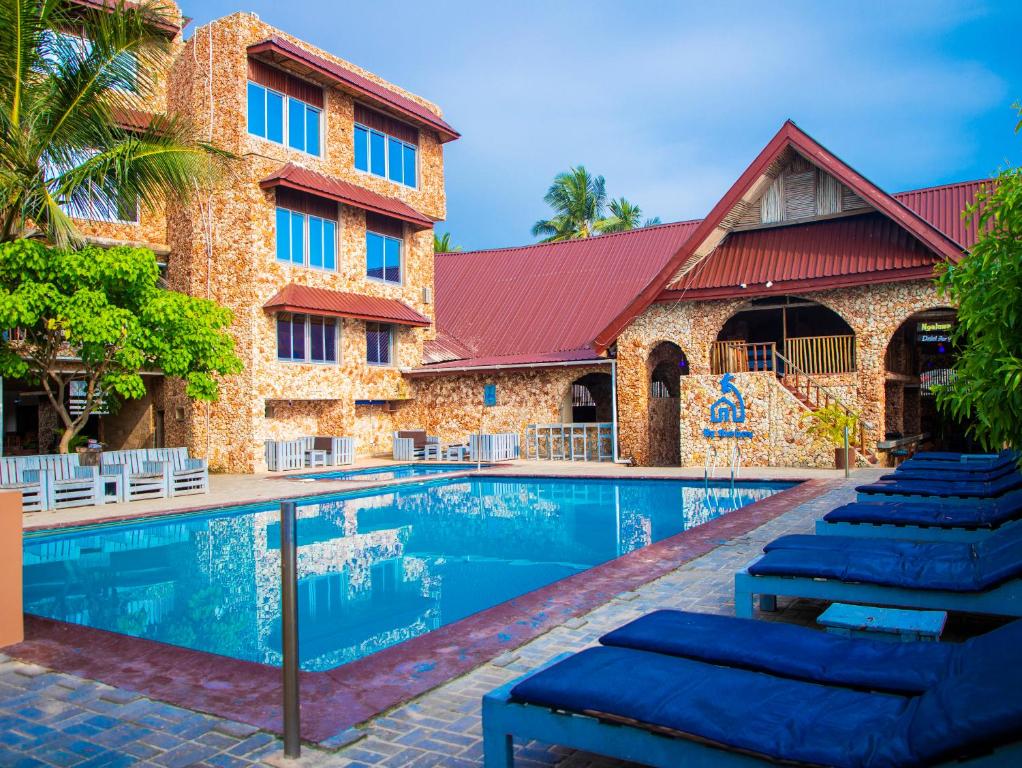 达累斯萨拉姆Serene Beach Resort的大楼前带躺椅的度假游泳池