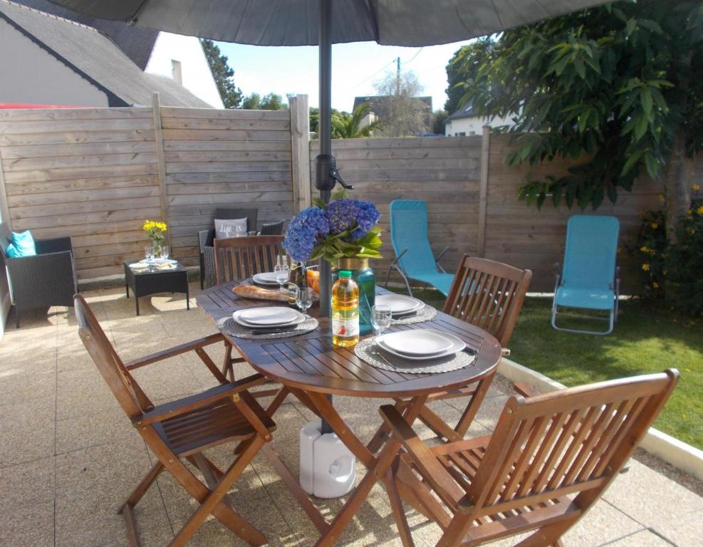 劳恩尼克Les hortensias的庭院里配有一张带椅子和遮阳伞的木桌
