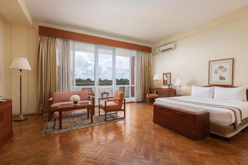 仰光茵雅湖酒店的大型酒店客房,配有床和椅子