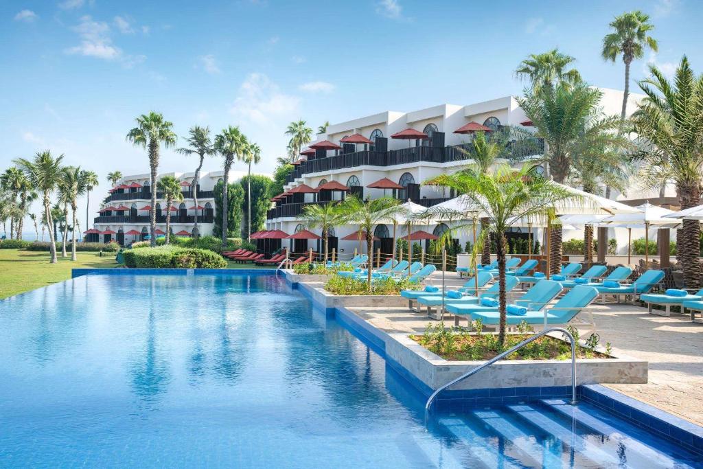 迪拜JA The Resort - JA Palm Tree Court的一个带游泳池、躺椅和棕榈树的度假村